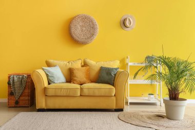 Sarı kanepeli ve çiçekli bir oturma odası.