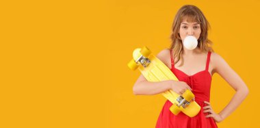 Sarı arka planda sakızı ve kaykayı olan zarif genç bir kadın.