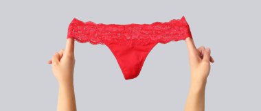 Gri arka planda seksi kırmızı külotlu kadın elleri