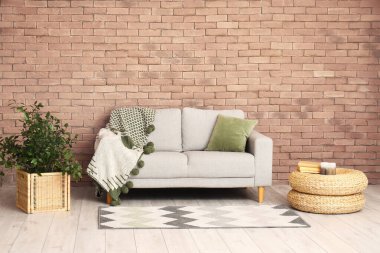 Modern oturma odasının içinde, tuğla duvarın yanında gri kanepe var.