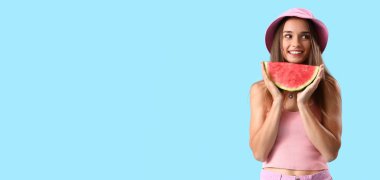 Açık mavi arkaplanda taze karpuz dilimi tutan genç bir kadın.
