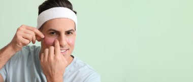 Açık yeşil arkaplan üzerinde göz altı yamaları uygulayan yakışıklı bir adam.