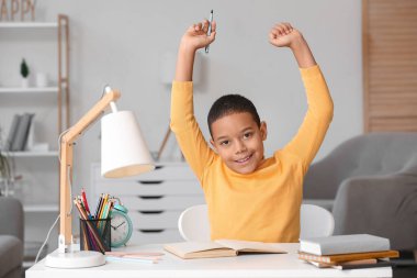 Küçük Afro-Amerikalı çocuk evde ders veriyor.