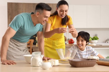 Mutlu ebeveynler ve küçük oğulları mutfakta hamur hazırlıyorlar.