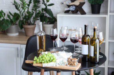 Bardaklar ve şarap şişeleri. Mutfaktaki masada atıştırmalıklar.