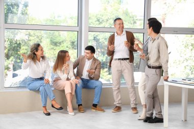 Bir grup iş adamı ofiste kahve içiyor.