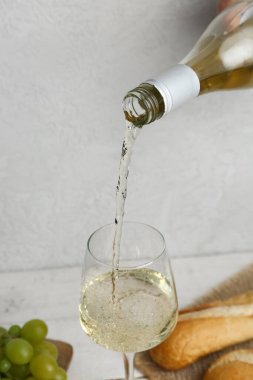 Beyaz şarap arka planda bardağa doluyor, yakın plan.