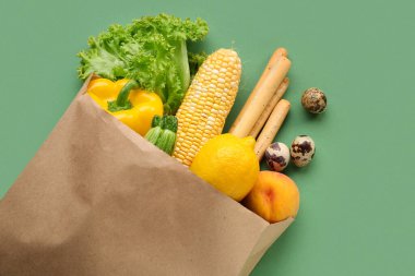 Yeşil arka planda taze sebzeli kağıt alışveriş torbası.