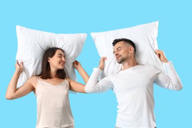 Mavi arka planda yumuşak yastıklı genç çift