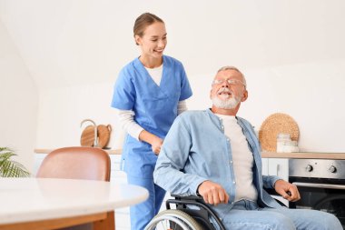 Tekerlekli sandalyedeki yaşlı adam ve evde hemşire.