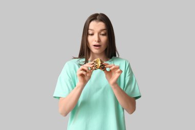 Gri arka planda lezzetli kurabiyeler olan şaşırmış genç bir kadın.