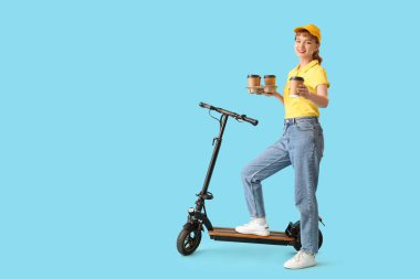 Portrait of female courier with takeaway coffee cups and kick scooter on blue background