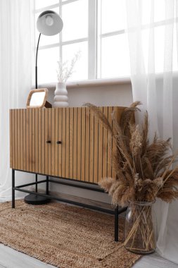 Vazo, lamba ve pencerenin yanındaki boş fotoğraf çerçeveli ahşap dolap.