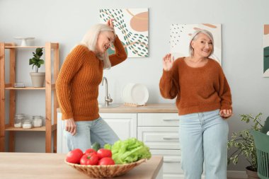 Olgun bayan arkadaşlar mutfakta dans ediyor.