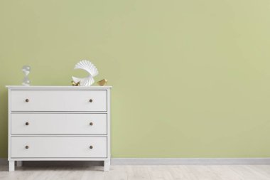 Yeşil duvarın yanında dekorlu modern çekmeceler.