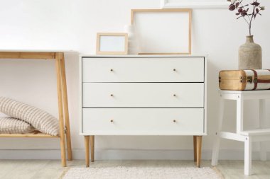 Çerçeveli dolap, merdiven ve masa beyaz duvarın yanında.