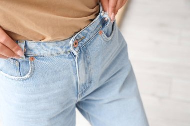 Yatak odasında modaya uygun kot giyen genç bir kadın, yakın plan.