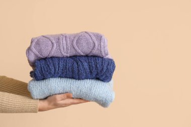 Bej arka planda katlanmış kazaklı bir kadın.