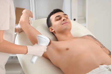 Kozmetik uzmanı kuaförde insan vücudundan saç çıkarmak için fotoepilatör kullanıyor.