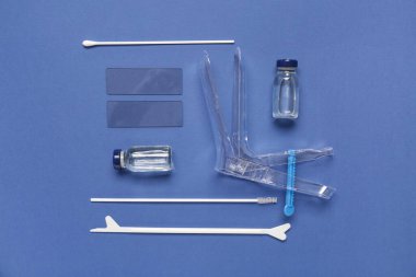 Pap smear test araçları ve mavi arka planda ampulleri olan jinekolojik spekulum