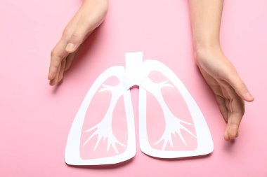 Pembe arka planda kağıt ciğerli kadın elleri