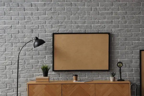 Çerçeveli ahşap dolap ve gri tuğla duvarın yanında lamba.