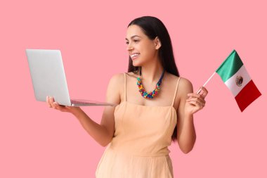 Pembe arka planda Meksika bayrağı ve laptopu olan genç bir kadın.