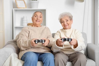 Üst düzey bayan arkadaşlar evdeki kanepede oyun oynuyorlar.