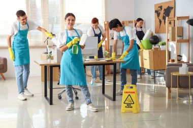 Genç hademeler ofiste temizlik yapıyor.