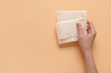 Bej arka planda regl pedleri olan bir kadın el.