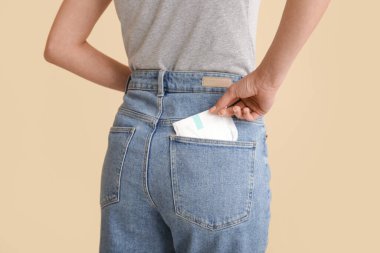 Bej arka planda regl pedi cebine koyan kadın