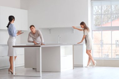 Emlakçı, genç çifte yeni evde mutfak gösteriyor.