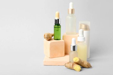 Hafif arkaplanda kozmetik ürünleri, zencefil ve alçı podyumları bulunan kompozisyon