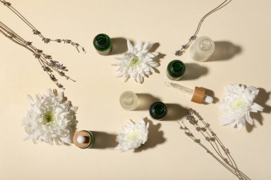 Renkli arka planda gerekli yağ şişeleri ve çiçeklerle kompozisyon