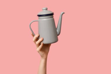 Pembe arka planda çaydanlığı olan kadın.