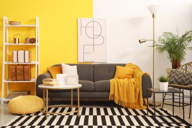 Masanın üzerinde kanepe, poster ve boş çerçeveler olan şık bir oturma odası.