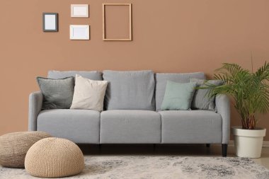 Oturma odasının içinde kanepe, puf ve boş fotoğraf çerçeveleri var.