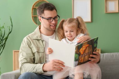 Mutlu bir baba ve tatlı küçük kızı evde masal okuyor.