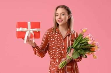 İşitme cihazı olan genç bir kadın pembe arka planda lale ve hediye tutuyor. Uluslararası Kadınlar Günü