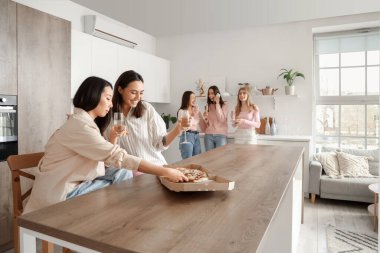 Şampanyalı genç kadınlar mutfakta Pizzalarını yiyorlar