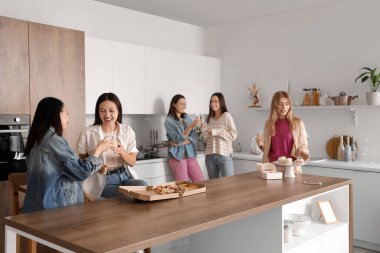 Şampanyalı ve abur cuburlu genç kadınlar mutfakta parti veriyor.