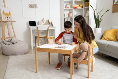 Ofiste resim çizen küçük bir çocukla kadın psikolog.