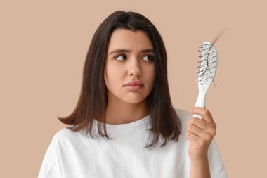 Bej arka planda saç dökülmesi sorunu olan stresli genç bir kadın.