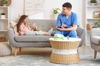 Doktoru olan küçük kız evdeki kanepede nebulizör kullanıyor.