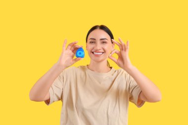 Diş ipiyle güzel, genç ve mutlu bir kadın sarı arka planda güzel bir jest yapıyor.