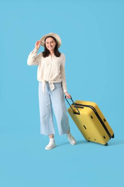 Mavi arka planda bavulu olan kadın turist.