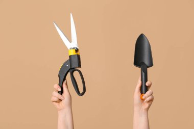 Renkli arka planda bahçe küreği olan kadın elleri, yakın plan.