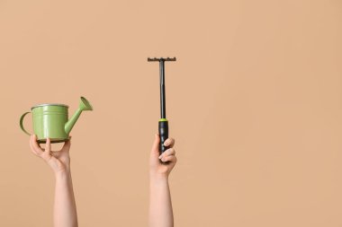 Sulama tenekesi olan kadın eller ve arka planda bahçe tırmığı, yakın plan