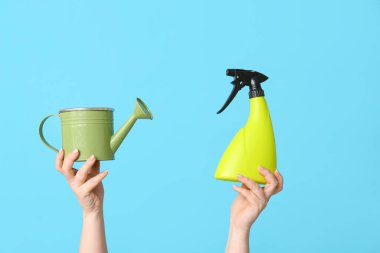 Sulama tenekesi olan kadın eller ve renk arkaplan üzerine sprey, yakın plan