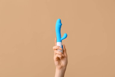 Renk arkaplanına karşı vibratörlü kadın eli, yakın plan